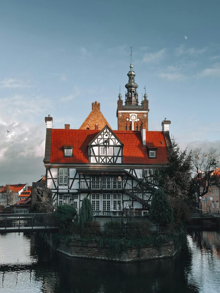 Charming clock tower and historical architecture in Gdańsk, Poland reflecting in water.