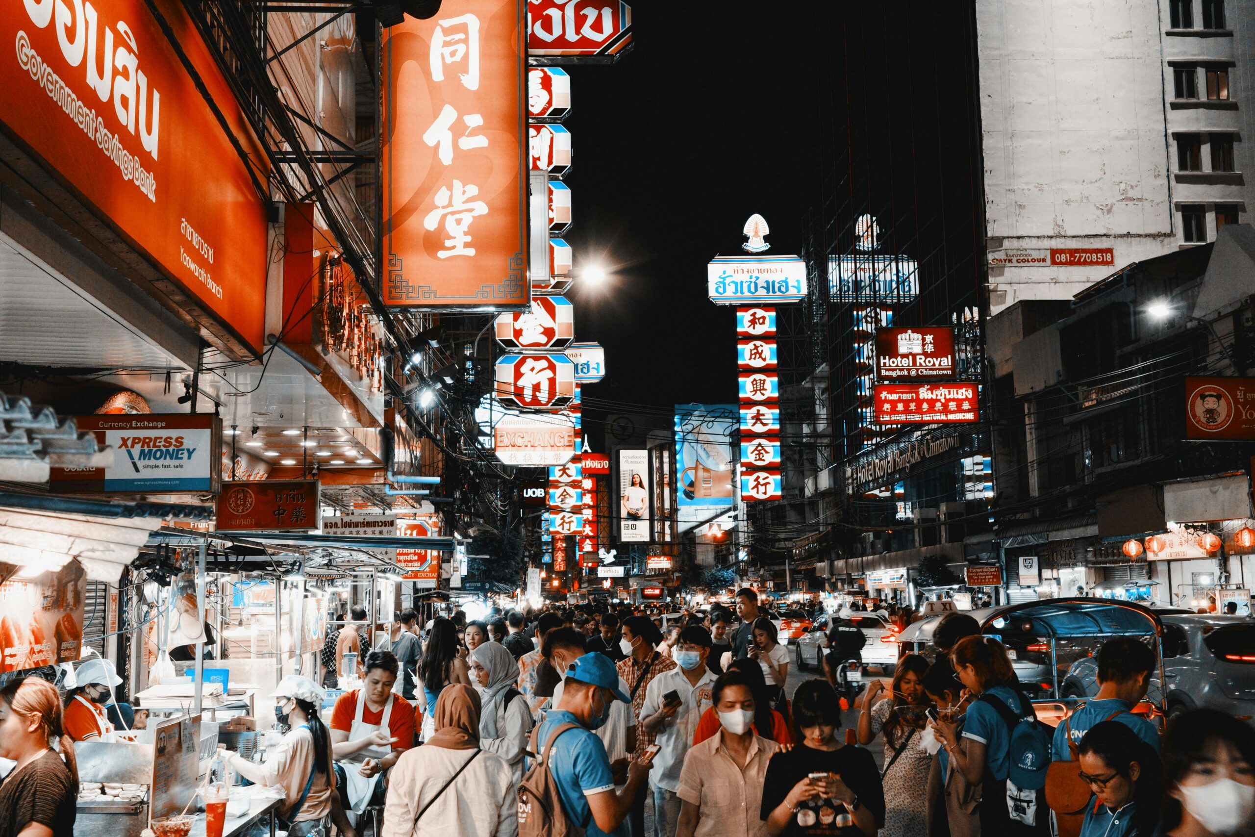 Vibrant night life on a busy street in Bangkok's Chinatown filled with lights and crowds.