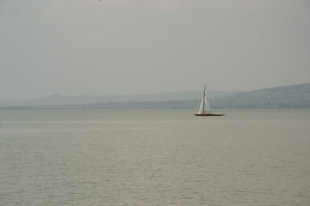 Tranquil scene of a sailboat on Lake Balaton, Hungary under a serene sky.