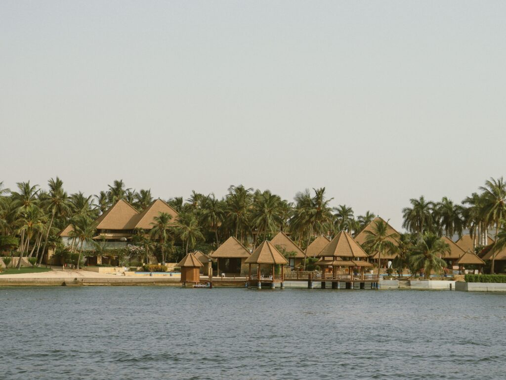 Serene tropical resort with palm trees and unique architecture by the waterfront.