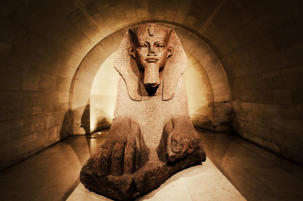 A captivating ancient Egyptian sphinx statue displayed inside a dimly lit museum corridor.