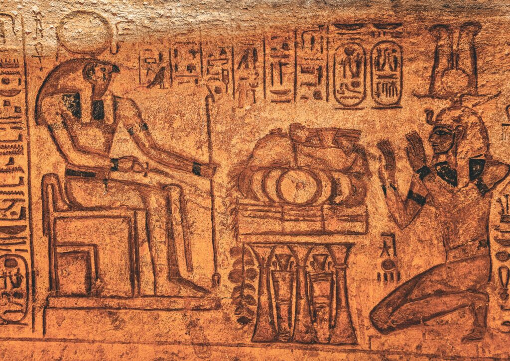 Detailed ancient Egyptian wall inscription with hieroglyphics and figures in sepia tones.