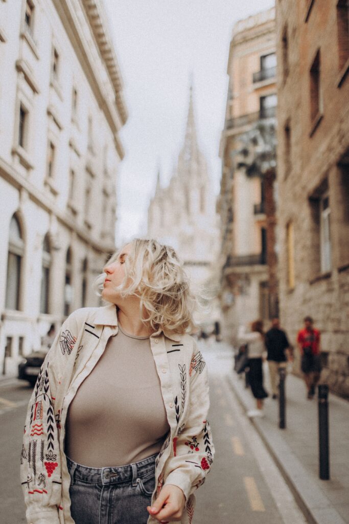 Blonde woman walking in a historic European street with a cathedral in the background.