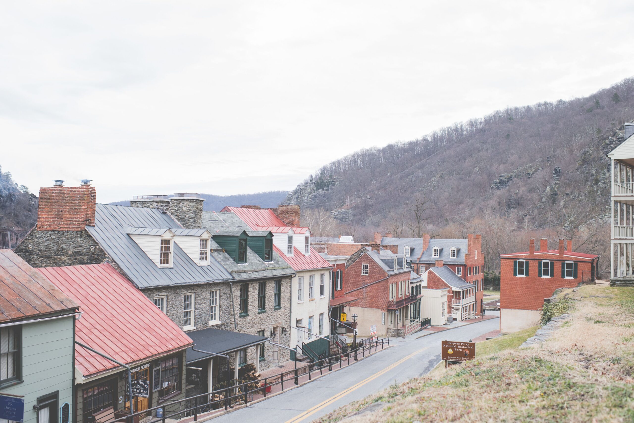 Picturesque view of a historic town with stone houses, chimneys, and a scenic mountain backdrop.