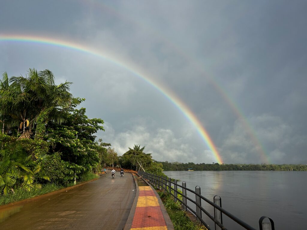Scenic view of a double rainbow arching over the Vaupés River in Colombia, with a bike path.