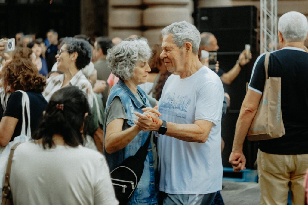 Senior couple dancing joyfully at an outdoor gathering, celebrating life and connection.