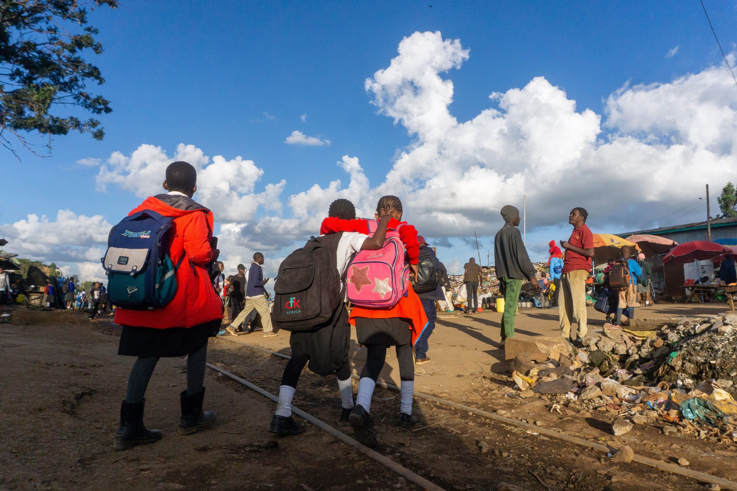 Children with backpacks walk along a street in Nairobi, capturing daily life and local culture.