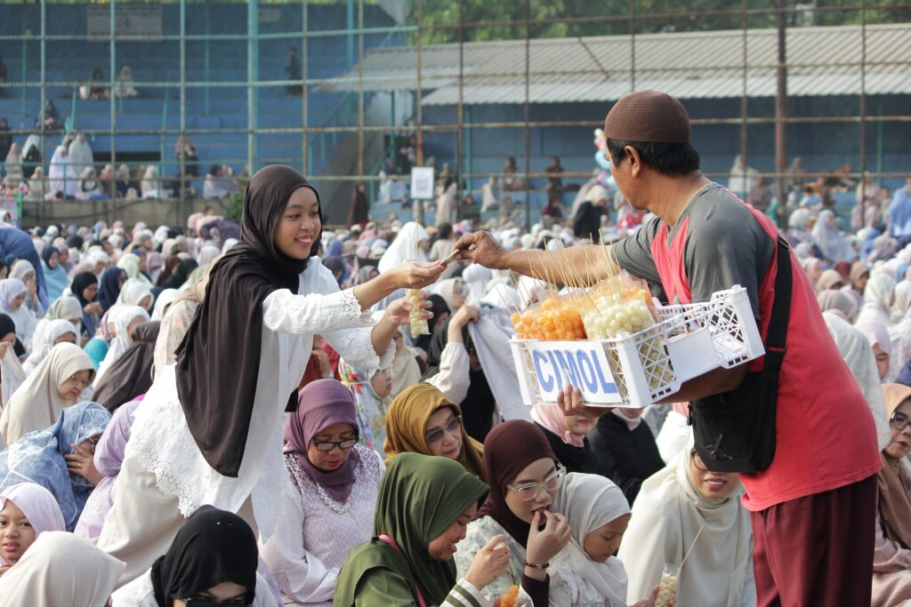 A vibrant gathering with people enjoying snacks from a vendor in Jawa Barat, Indonesia.