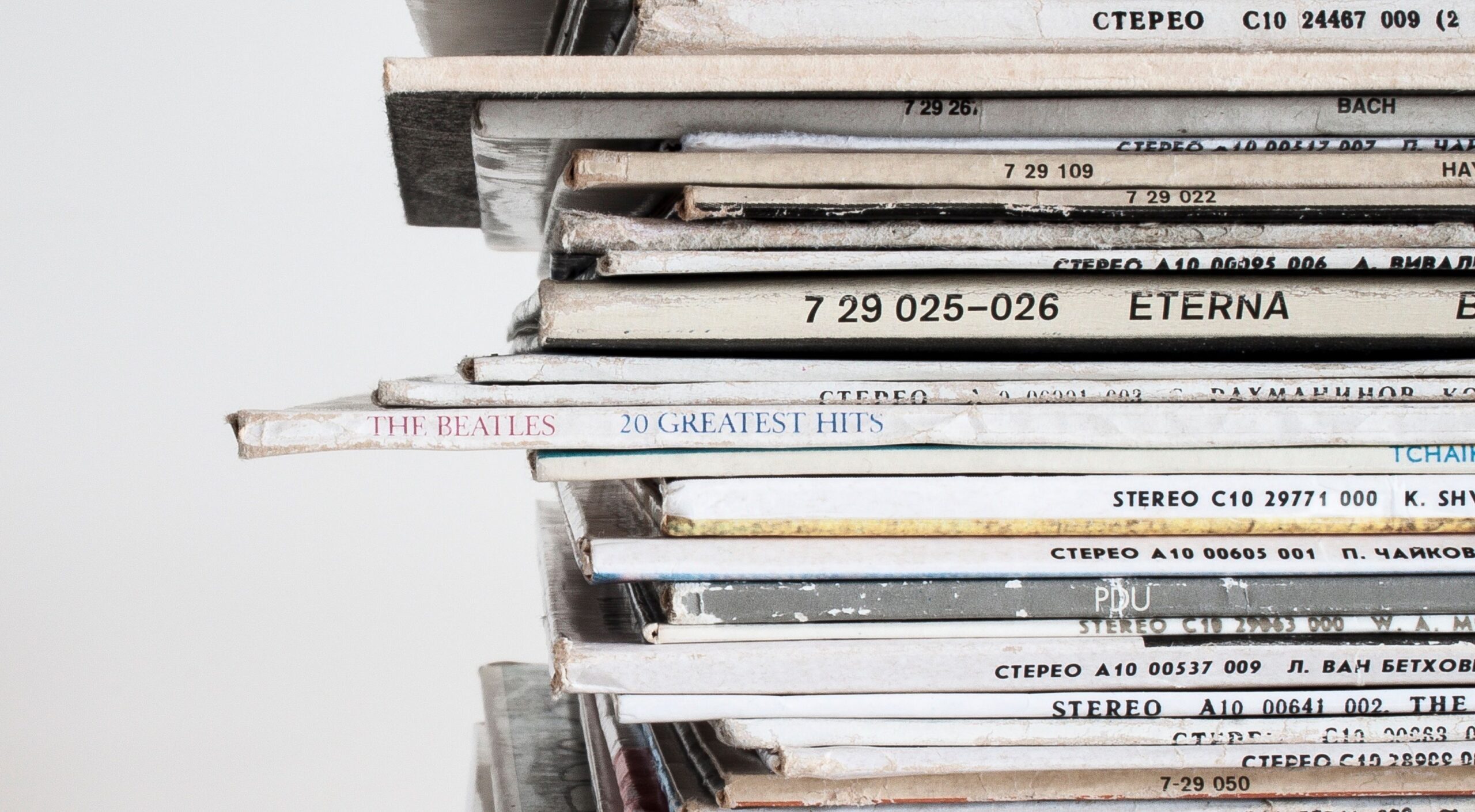 Close-up shot of a stacked pile of vintage vinyl record albums showcasing classic music covers.