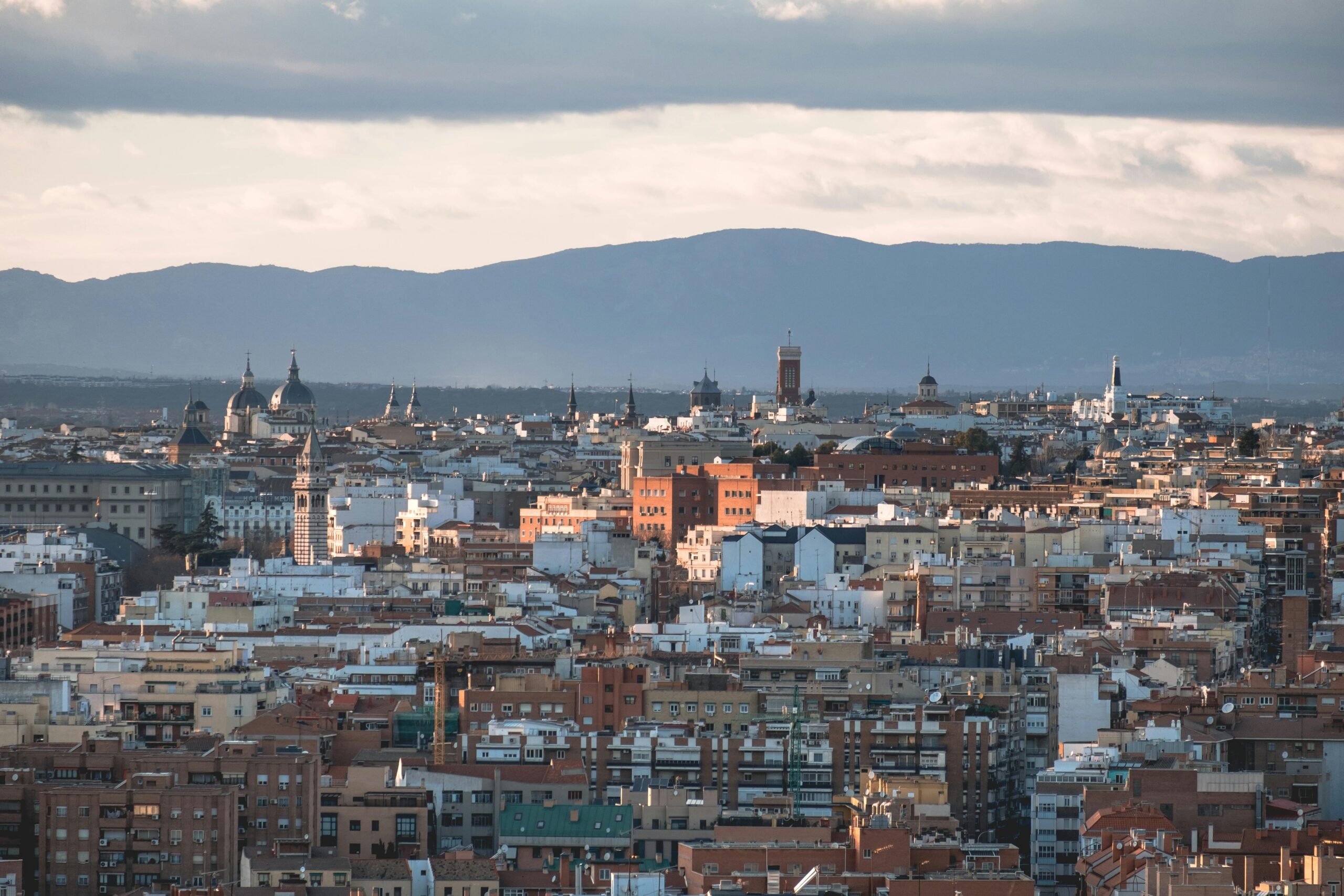 A stunning aerial shot showcasing Madrid's vibrant cityscape with iconic landmarks and mountains in the backdrop.