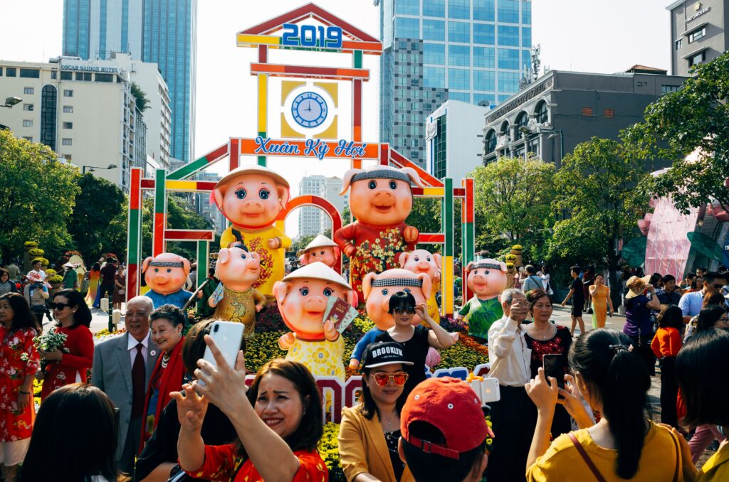 Crowds enjoy the colorful Tet festival with pig statues in urban Vietnam, 2019.