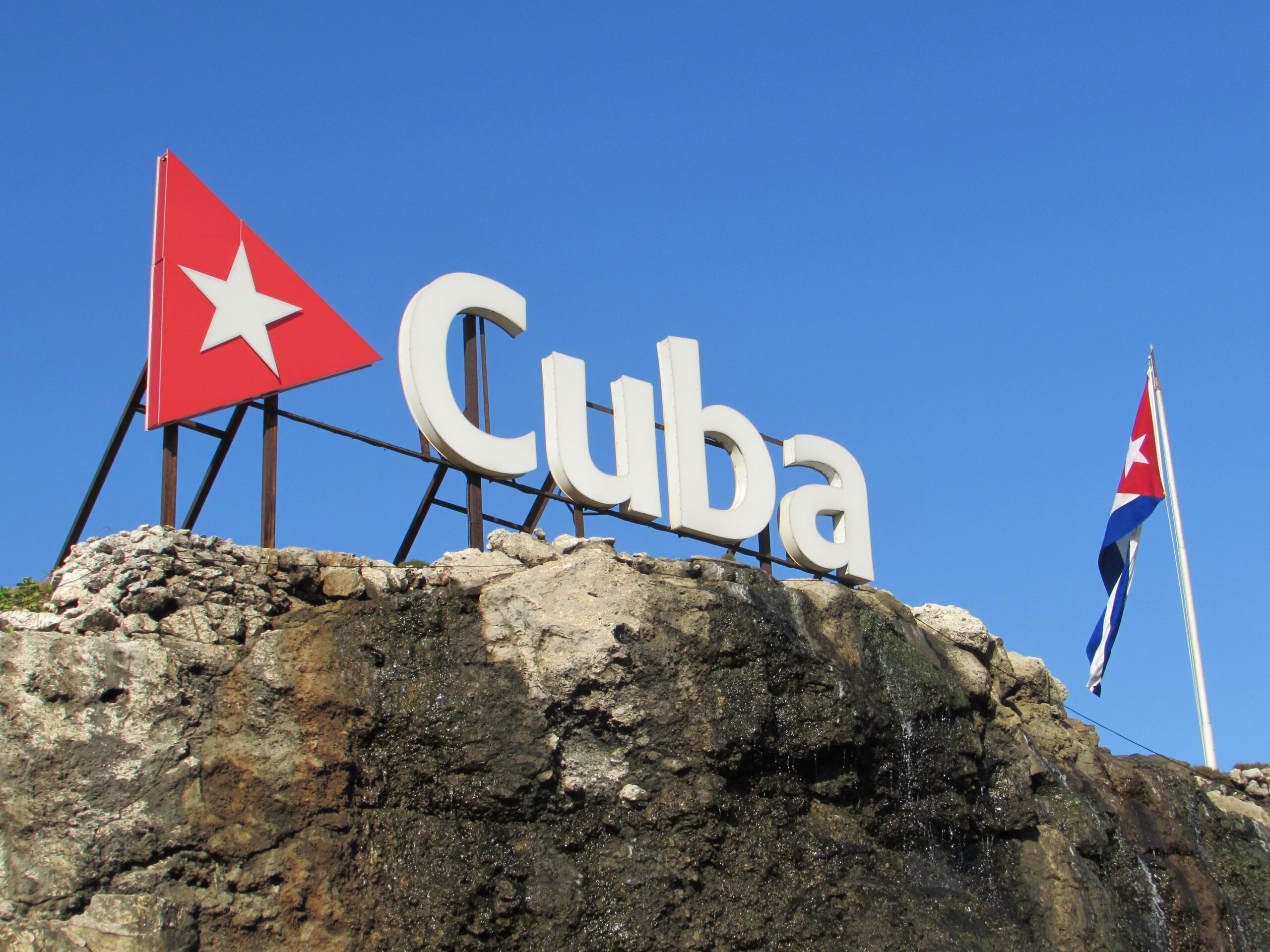 Cuba sign and flag against a clear blue sky in Havana, Cuba.