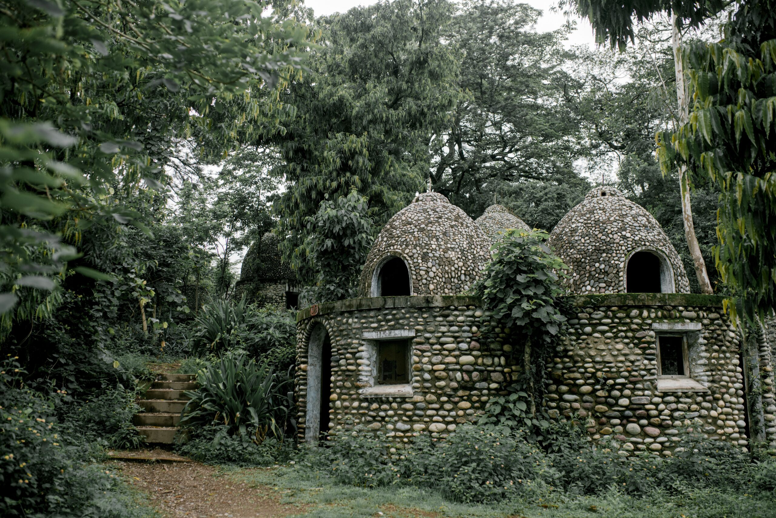 Facade of ancient stone Buddhist meditation caved surrounded by green lush tropical vegetation in Beatles Ashram