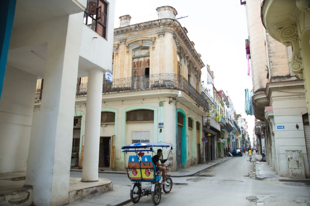 Exterior of aged stone residential buildings and narrow asphalt roadway situated on in old Havana city district in daylight