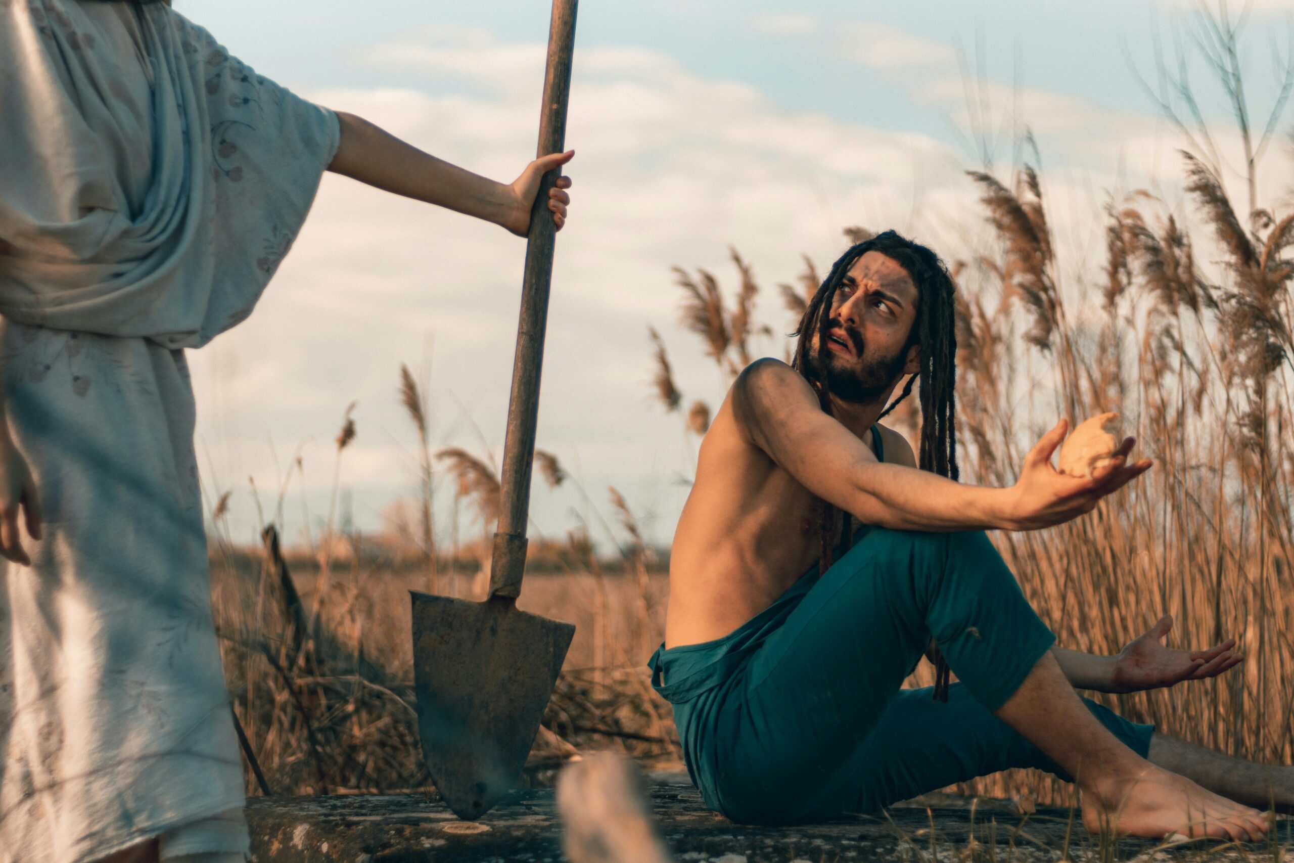 A contemplative man in a rustic field scene holding a rock.