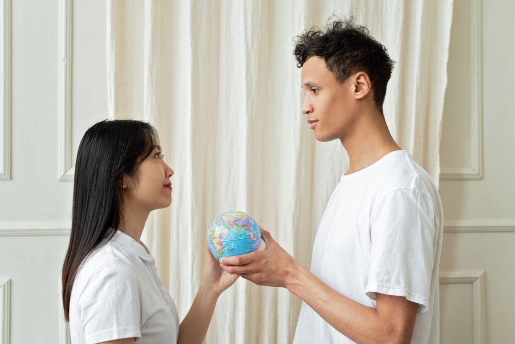 A couple holds a small globe, symbolizing diversity and unity indoors.