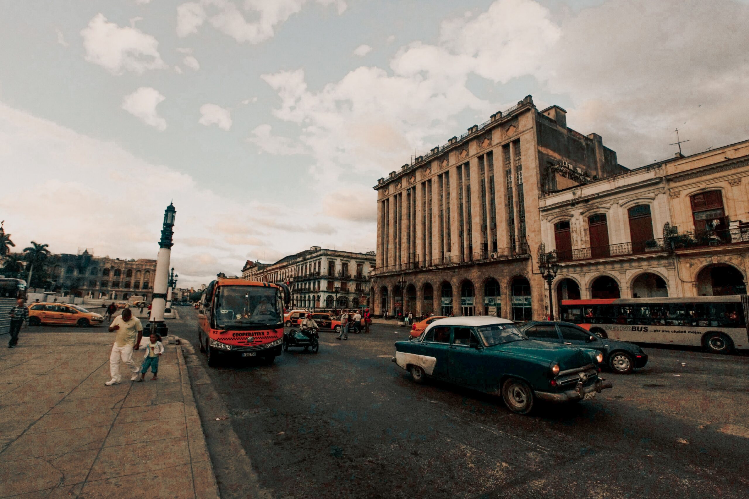 A vibrant Havana street scene showcasing vintage cars and historic architecture under a cloudy sky.