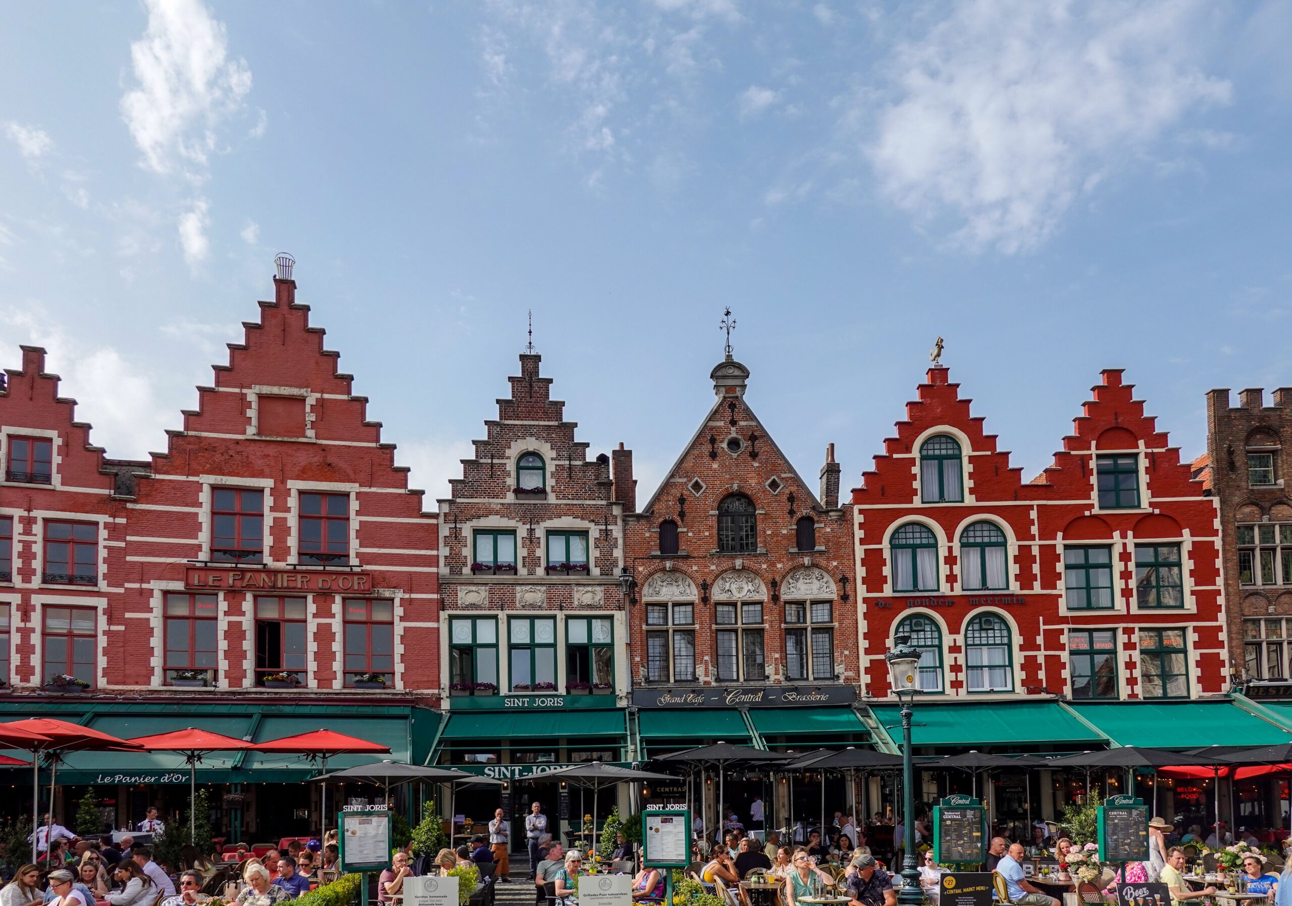 Charming gabled townhouses in Bruges Market Square, showcasing vibrant architecture and bustling atmosphere.
