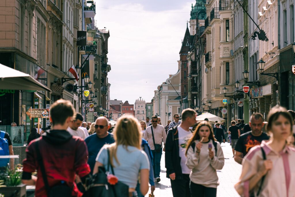 Vibrant urban street scene in Toruń, capturing people and historic architecture on a sunny day.