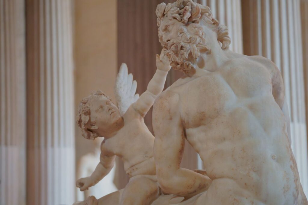 Detailed view of a marble sculpture inside the Louvre Museum, Paris, depicting mythological figures.