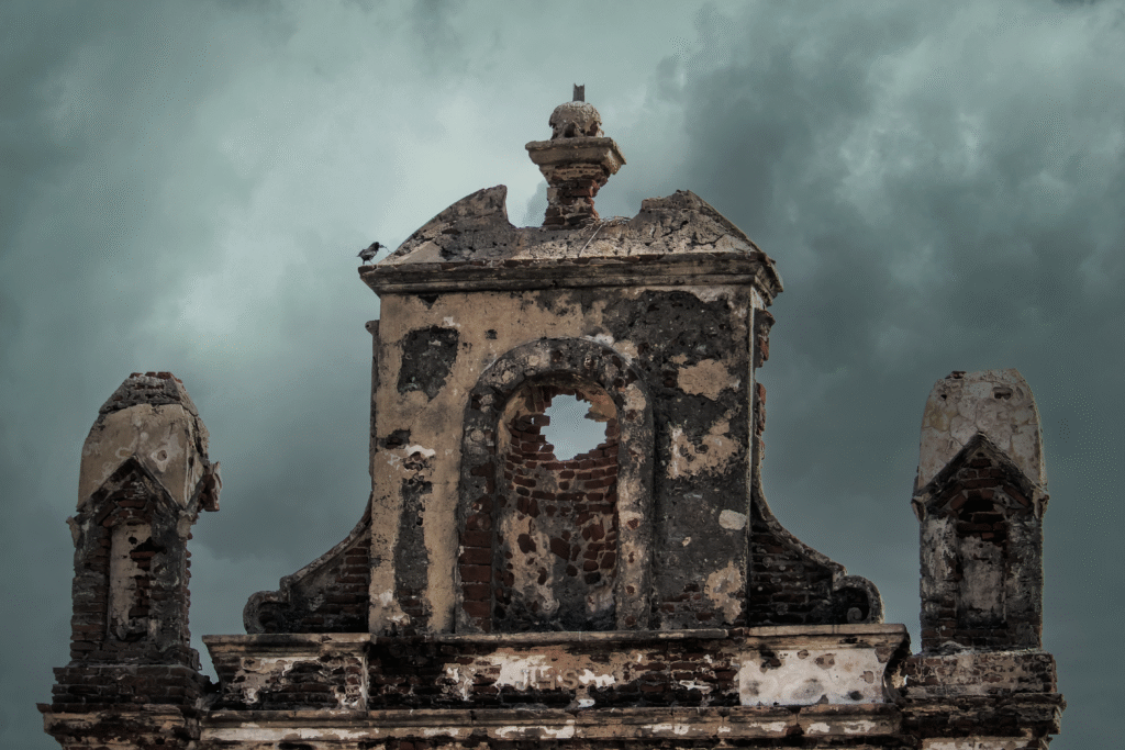 Weathered ruins of an old church facade set against a moody stormy sky.