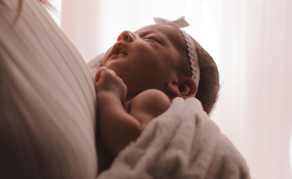 Serene image of a sleeping baby resting peacefully in a mother’s embrace.