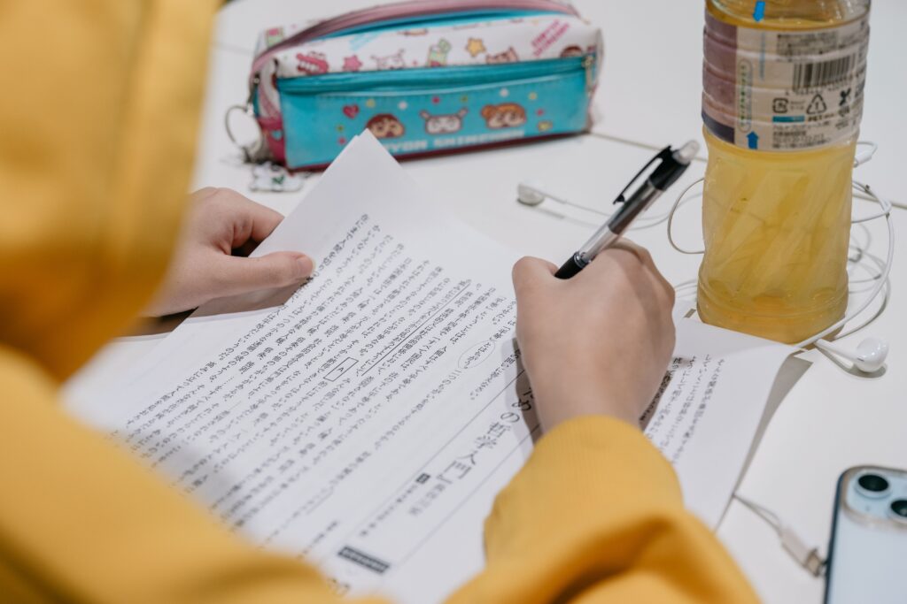 Close-up of individual studying Japanese text with colorful stationery on desk.