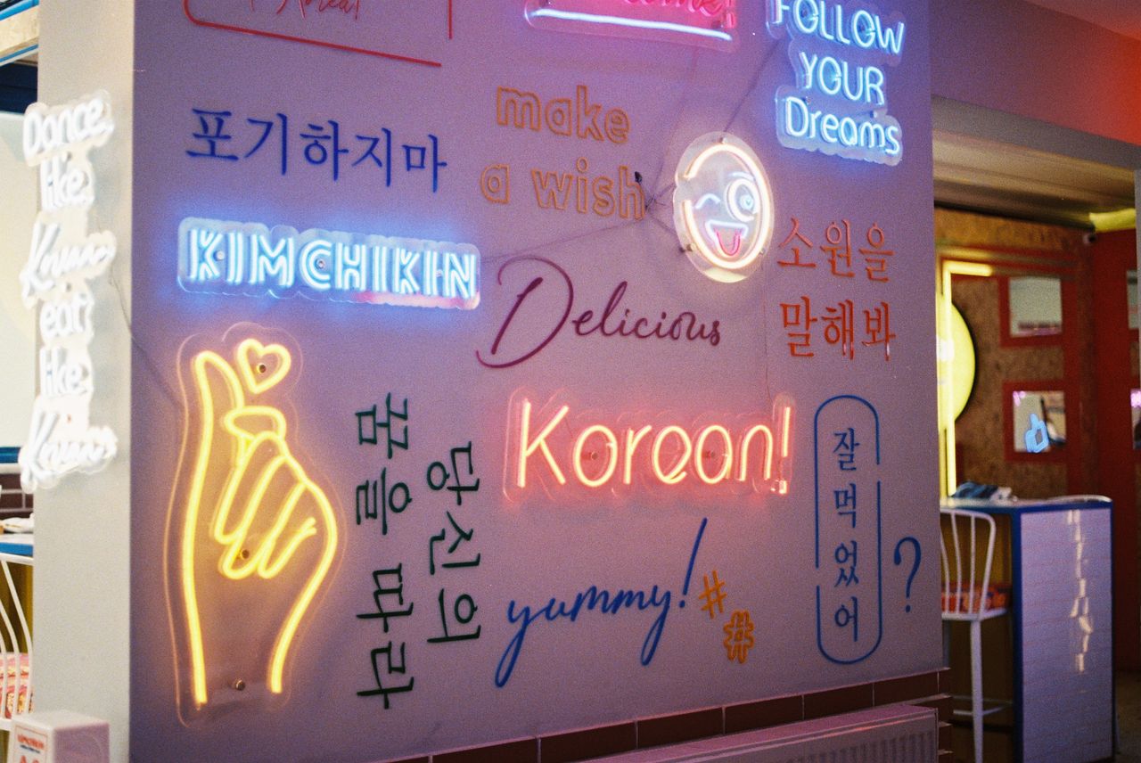 Vibrant neon signage in a café, showcasing Korean and English phrases.