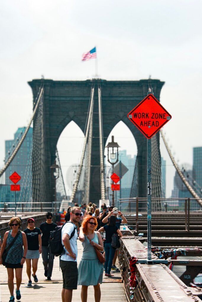 A lively scene with tourists walking on the iconic Brooklyn Bridge in New York City.