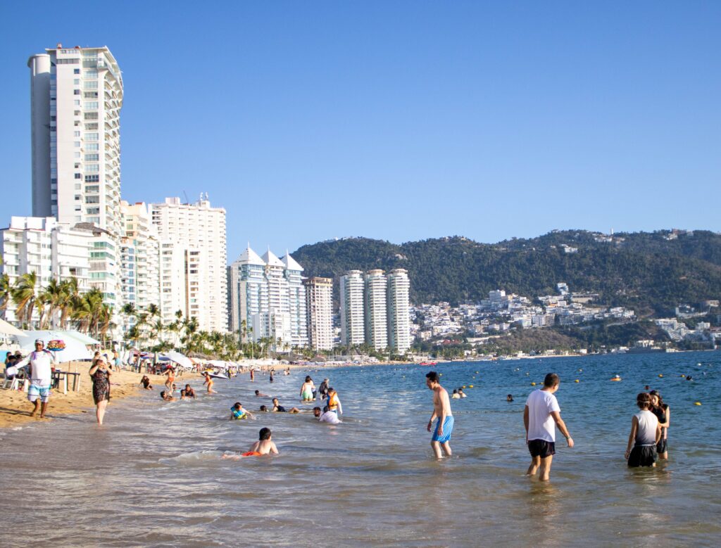 Vibrant beach scene at Acapulco, Mexico with people enjoying the sunny coastline.