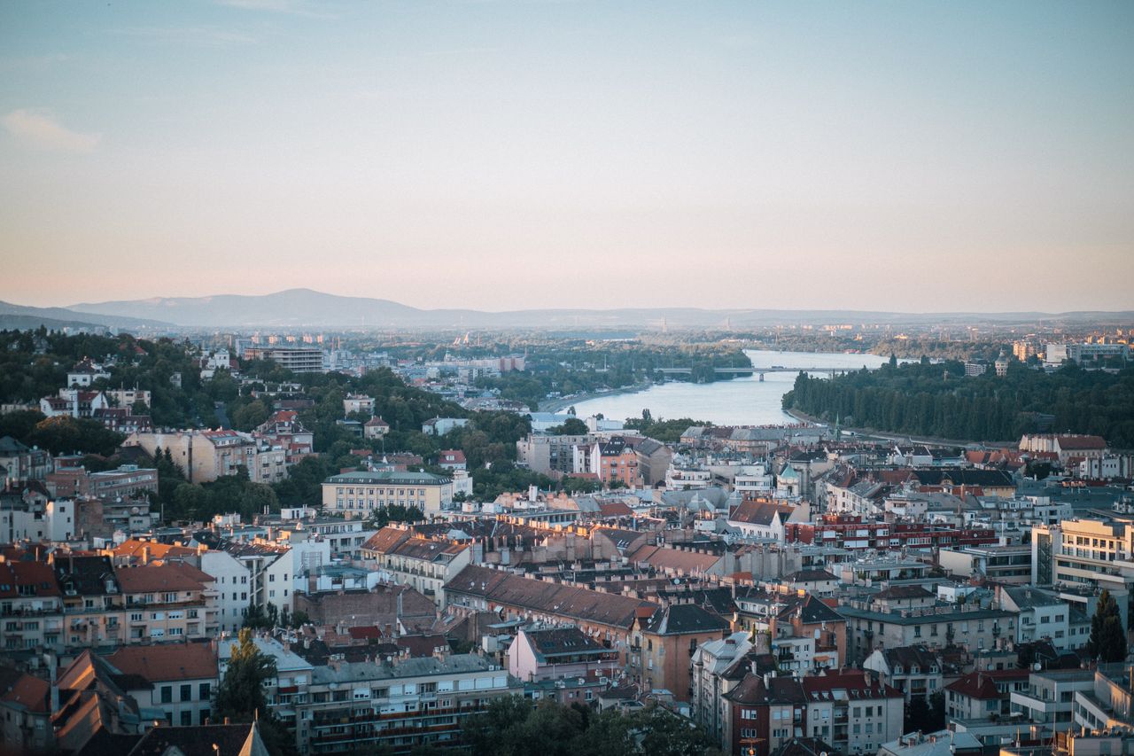 Aerial shot of Budapest with the Danube River and city architecture during sunset.