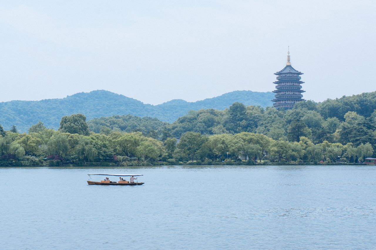 Peaceful scene featuring a boat on West Lake with Leifeng Pagoda in Hangzhou, China.
