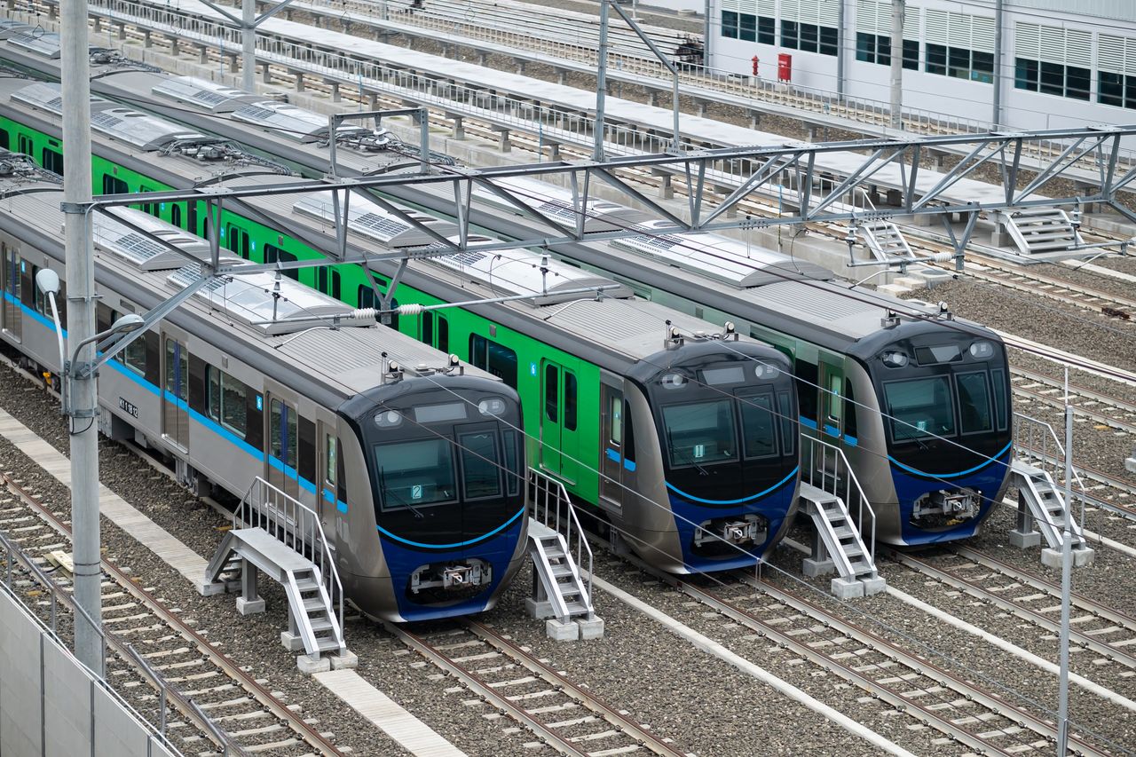 Three modern trains parked on tracks in a railway station in Jakarta, Indonesia.