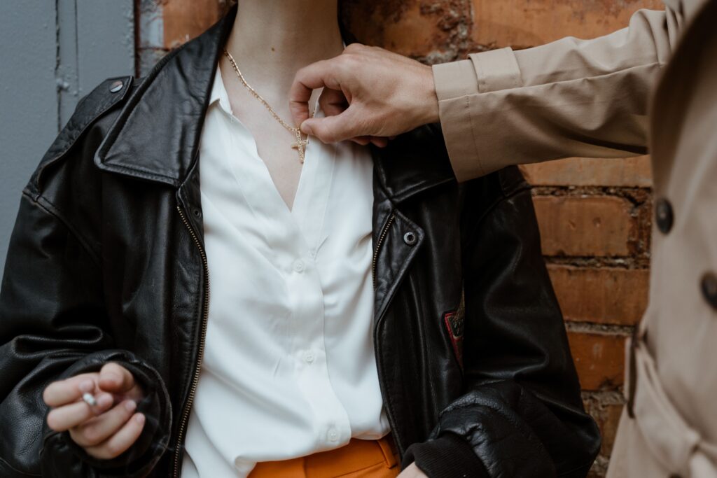 Close-up of a hand adjusting a necklace on a stylish outfit with a leather jacket.