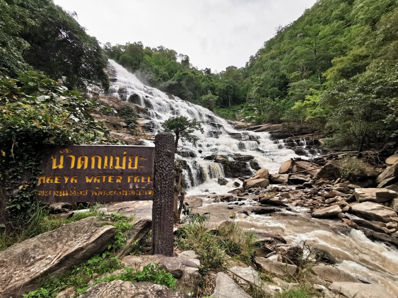 Scenic view of Mae Ya Waterfall in Thailand, cascading over rocks amidst lush greenery.