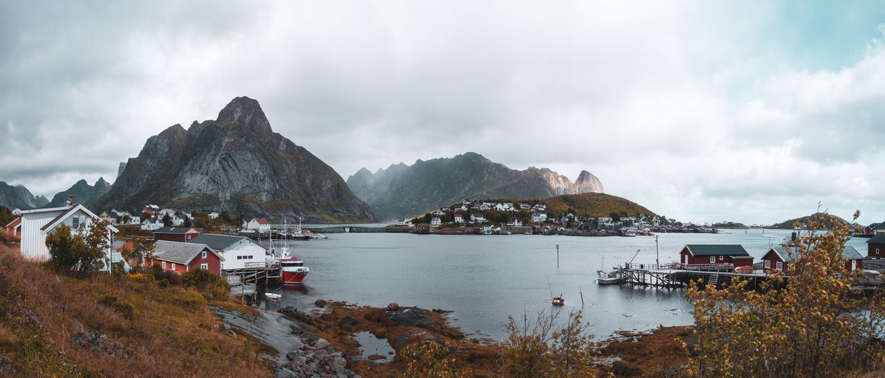 Breathtaking panoramic view of Reine, Norway, showcasing red cabins, mountains, and a tranquil fjord.