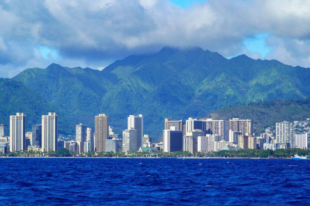 Stunning aerial view of Honolulu's skyline with lush mountains and ocean in foreground.