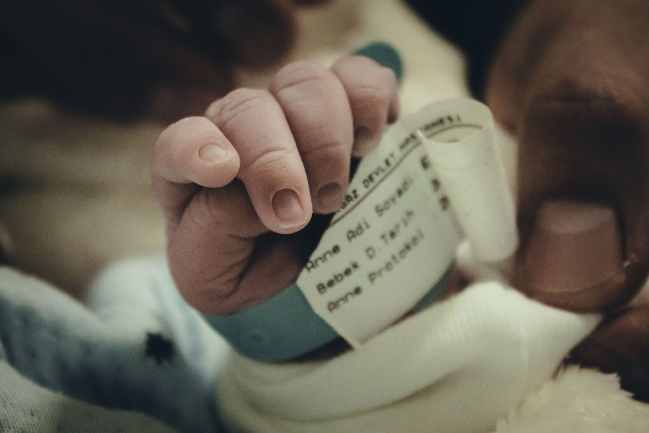 Close-up of a newborn baby's hand with a hospital wristband, symbolizing new life and care.