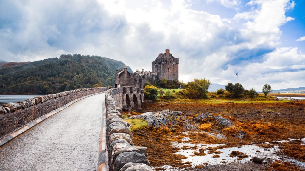 Scenic view of Eilean Donan Castle and bridge under cloudy sky in Scotland.