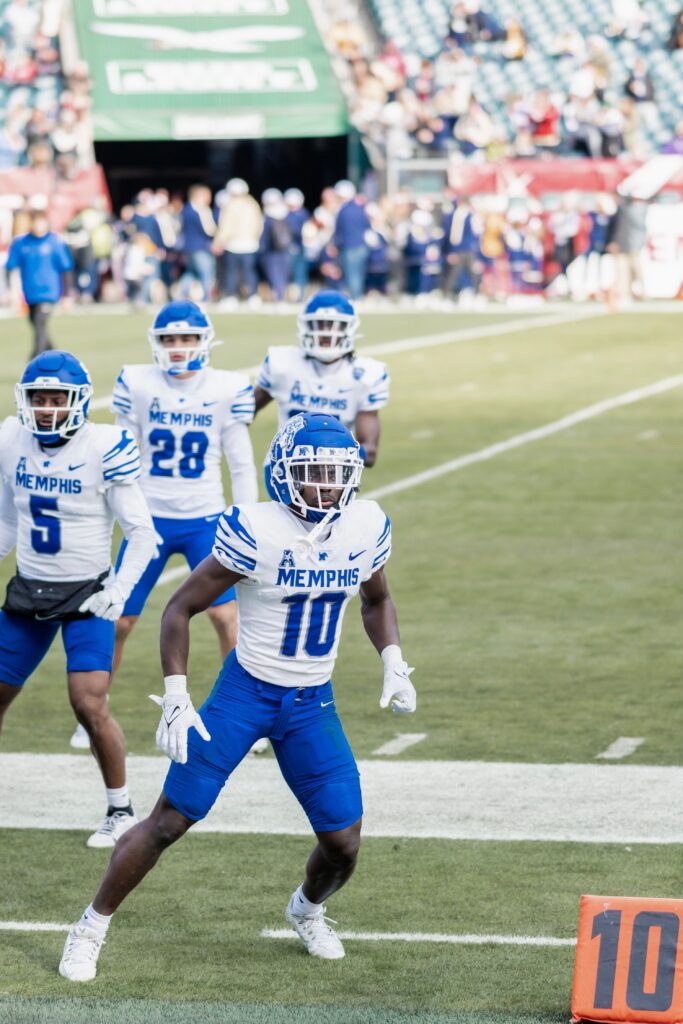 Memphis Tigers football players on the field during a game, focusing on teamwork and athleticism.