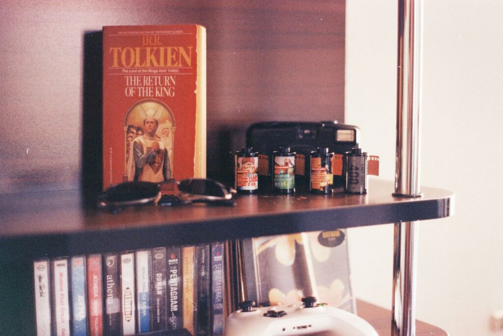 A vintage scene featuring a J.R.R. Tolkien book, sunglasses, camera film rolls, and a bookshelf.