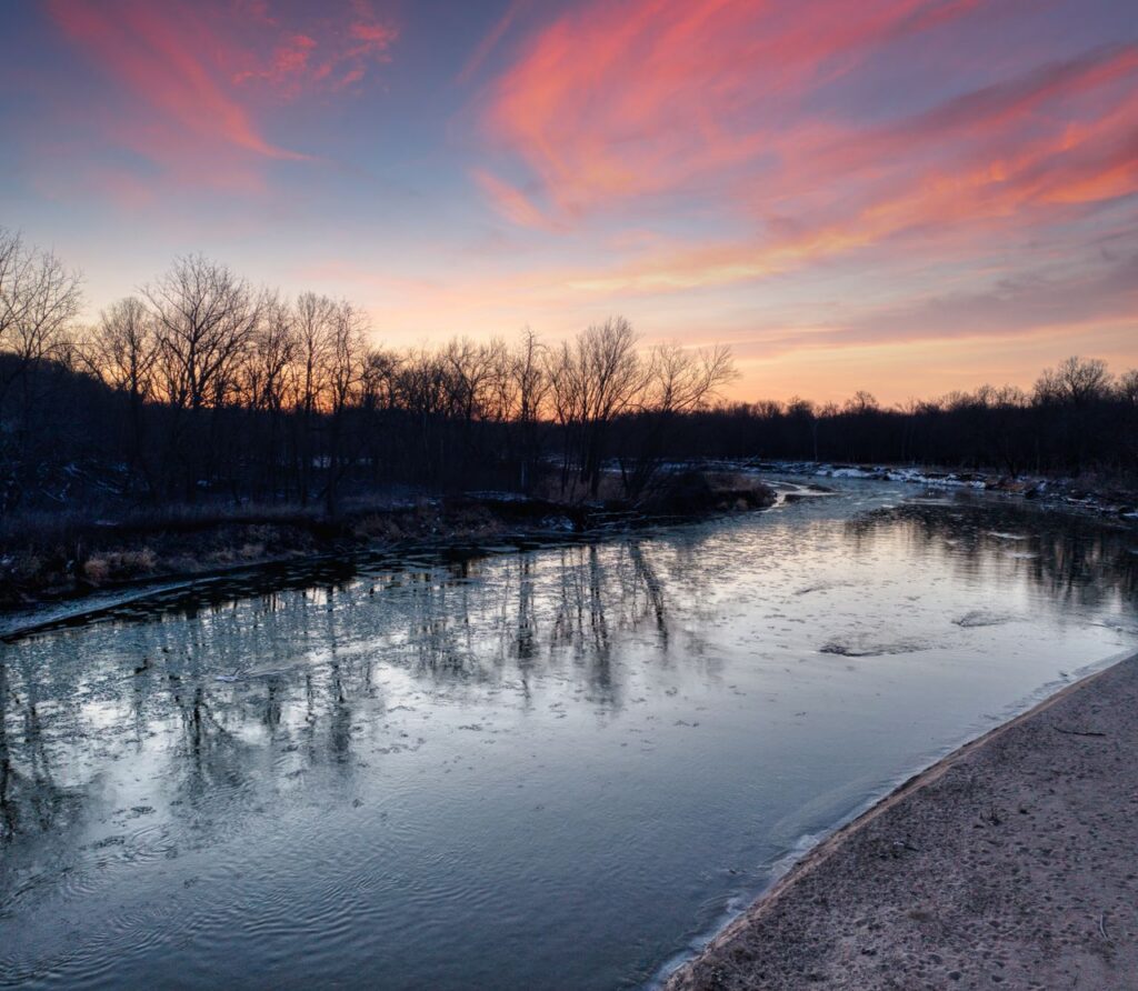 Peaceful river scene with bare trees at twilight in Kellogg, Minnesota.
