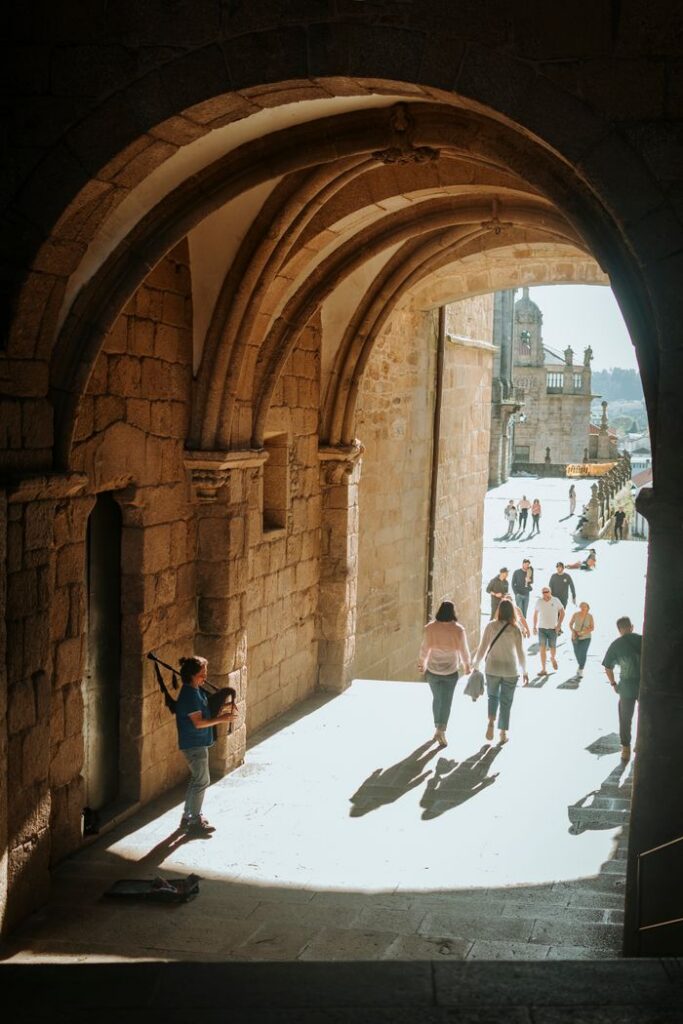 People walking through a historic archway in a sunlit urban scene, capturing vibrant daily life.