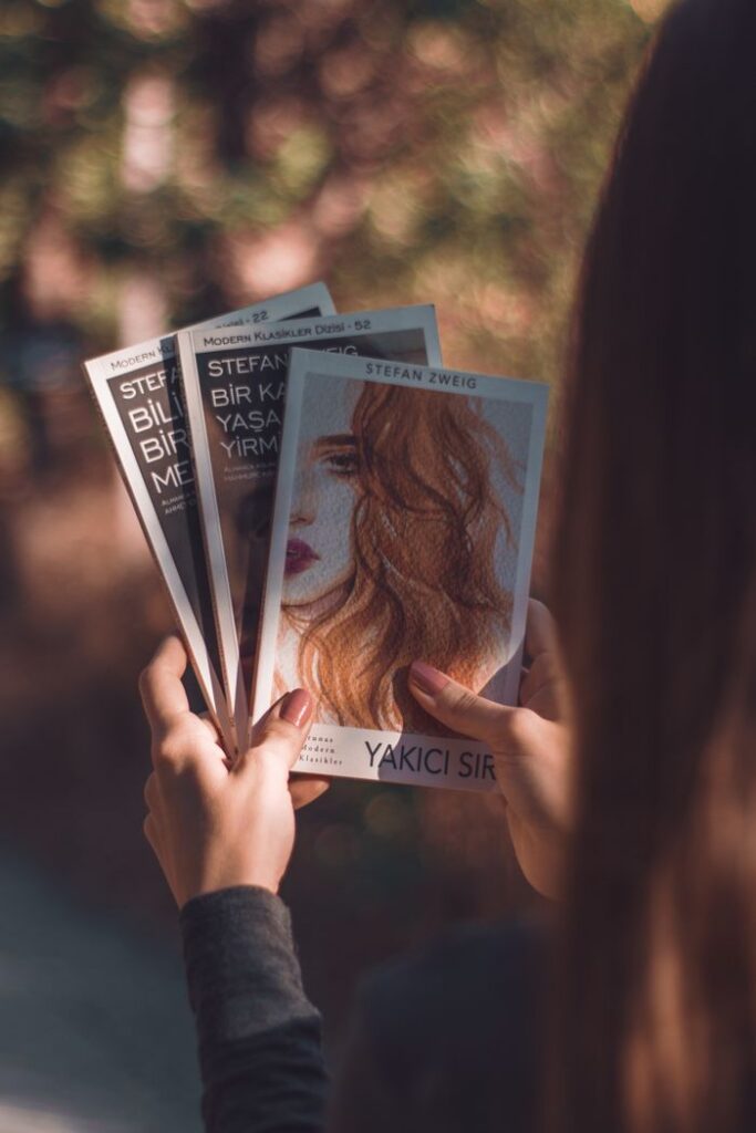 Individual holding Stefan Zweig novels in a serene outdoor setting, featuring Yakıcı Sır cover.