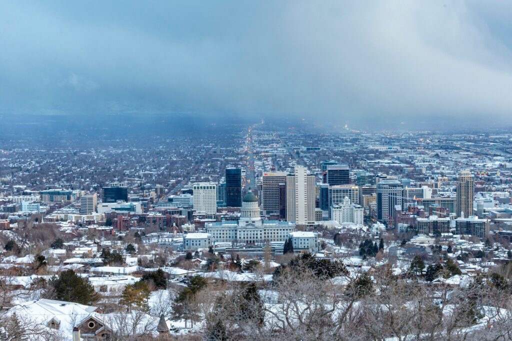 Aerial view of a snow-covered cityscape featuring prominent buildings under a cloudy sky.