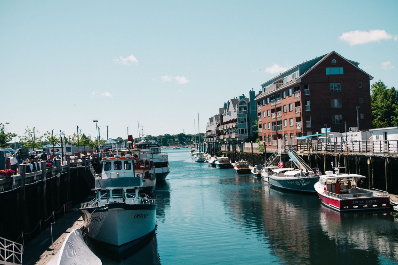 Scenic view of boats docked at a vibrant harbor beside brick buildings.