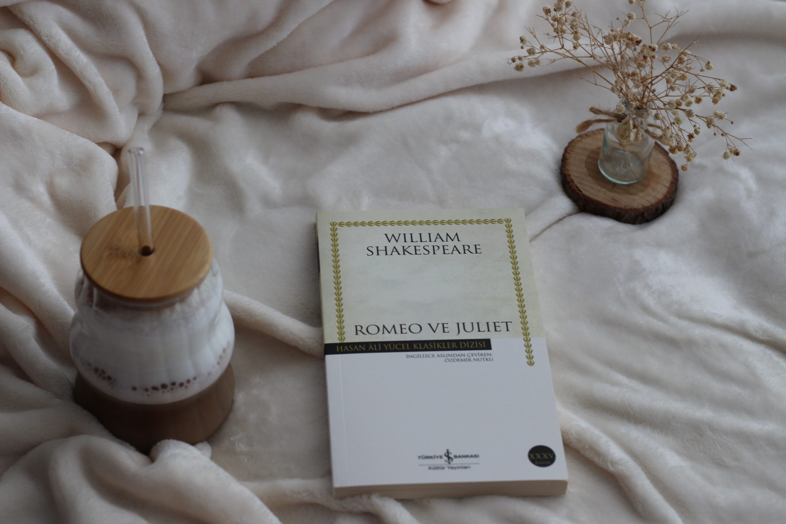 A serene indoor scene with a Romeo and Juliet book, coffee and dried flowers.