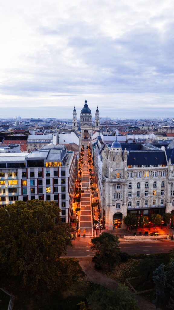 Stunning aerial view of illuminated St. Stephen's Basilica and Andrassy Avenue in Budapest at dusk.