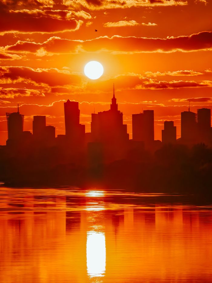 A dramatic city skyline silhouetted against a vibrant, fiery sunset.
