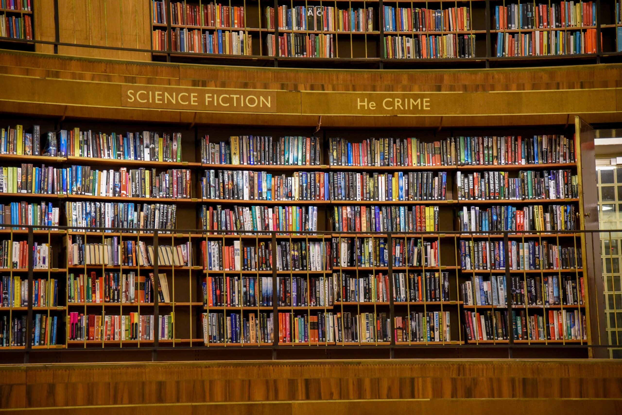 City library with wooden bookshelves and assorted literature with colorful covers put in rows